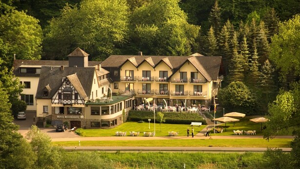A hotel with a traditional European architectural style, featuring multiple balconies and a central courtyard with outdoor seating. - Moselhotel Restaurant Peifer (Brodenbach)