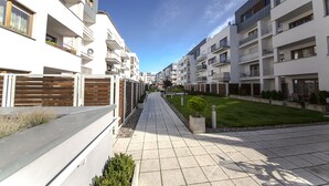 Un immeuble résidentiel moderne doté de balcons, d’une allée pavée et d’une pelouse bien entretenue.