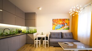 Une cuisine moderne avec un coin repas, un canapé gris et un tableau coloré accroché au mur.