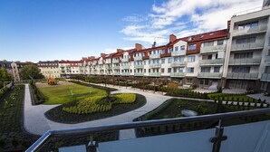 Un ensemble immobilier résidentiel comprenant plusieurs balcons, un espace paysager central agrémenté de sentiers et un ciel dégagé.