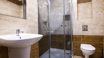Ein modernes Badezimmer mit einer Duschkabine, einem Standwaschbecken und einer Toilette.