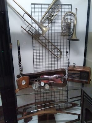 Une exposition de divers instruments de musique en laiton, notamment une trompette, un trombone et une clarinette, disposés sur un panneau mural à grilles.