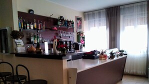 Un espace bar avec un comptoir, des tabourets, ainsi que diverses bouteilles et verres.