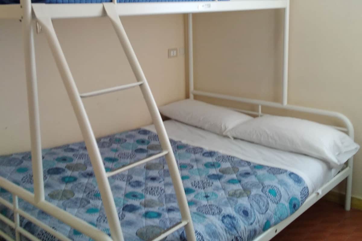 Ein Stockbett mit einer blauen und weißen gemusterten Matratze und weißer Bettwäsche.