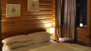 Une pièce de style cabane en bois, avec un lit, une chaise et deux tableaux encadrés accrochés au mur.