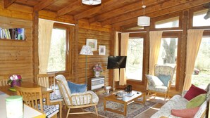 L’intérieur chaleureux d’un chalet en bois, avec des murs en bois, un coin repas, un canapé et un téléviseur.