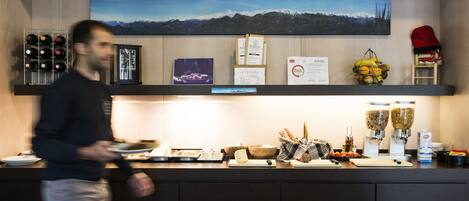 Una encimera de cocina con vistas a la montaña, una botella de vino en una estantería y una cafetera.
