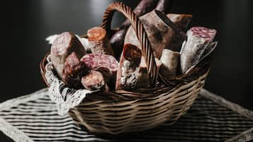 A basket of various cured meats and cheeses on a striped cloth.