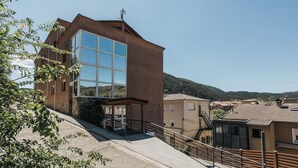 A modern building with large windows and a covered entrance. - La Trobada Hotel Sport (Ripoll)