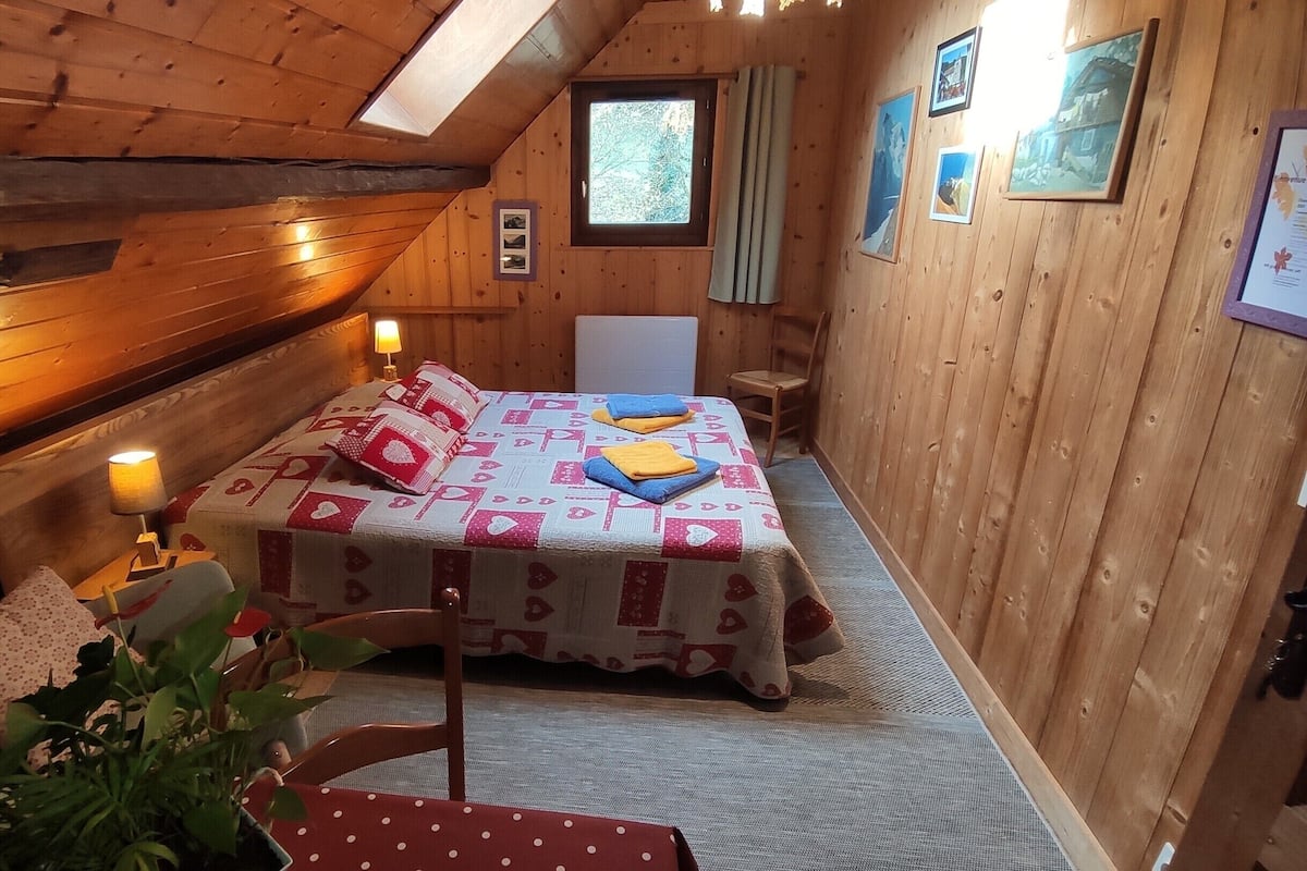 Una habitación acogedora de madera con una cama, una mesita y una silla.
