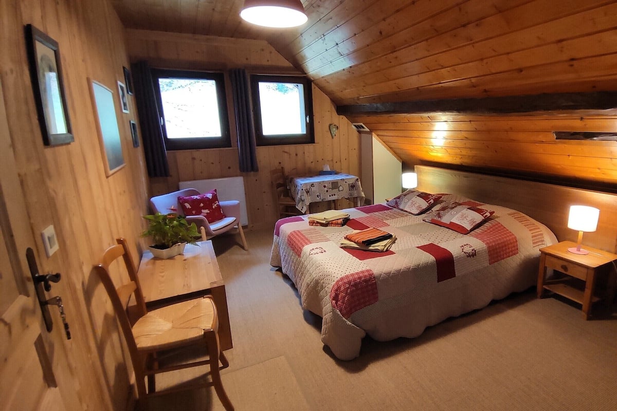 Un dormitorio acogedor con muebles de madera, cama, mesita de noche, silla y una pequeña mesa con lámpara.