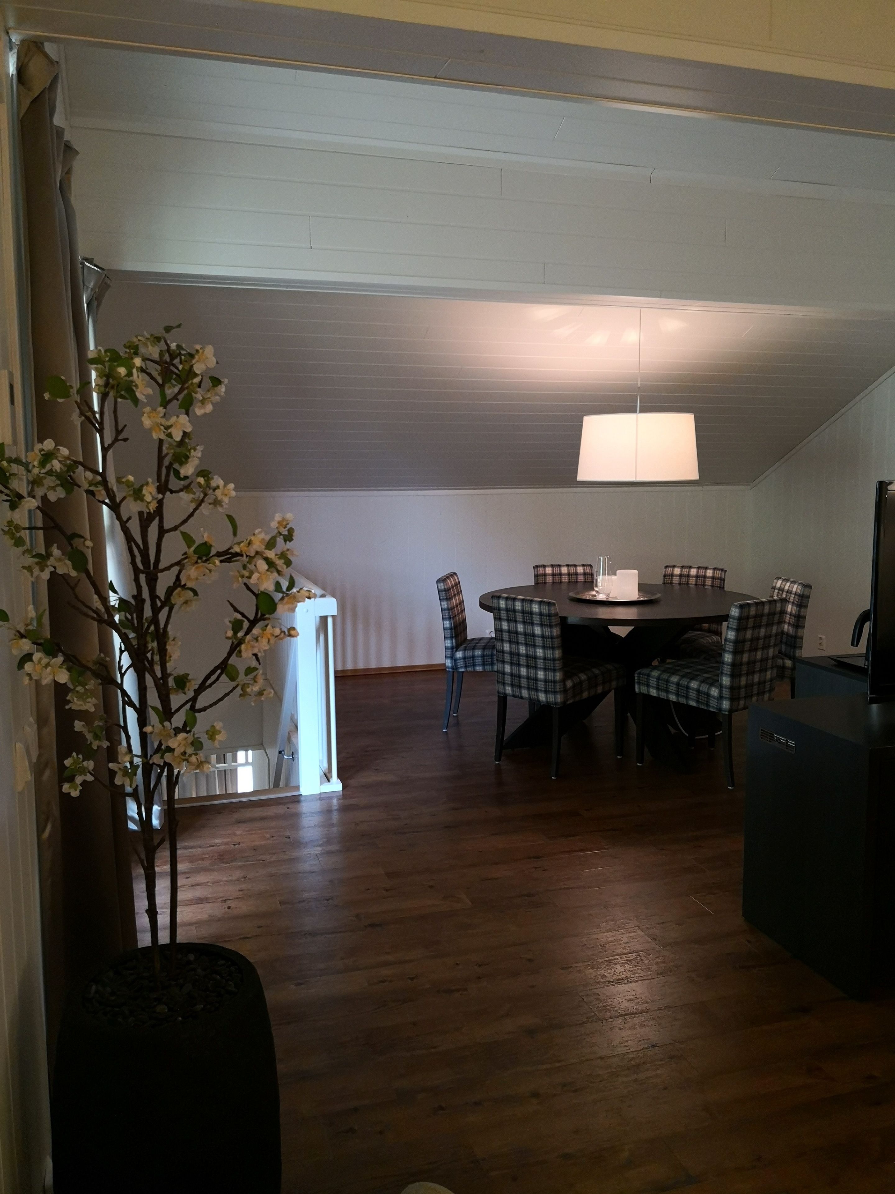 A dining area with a round table and plaid chairs, a lamp, and a small plant.
