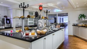 Une cuisine moderne dotée d’un grand îlot central, équipé d’une machine à café, de divers récipients de conservation et d’un lustre décoratif.