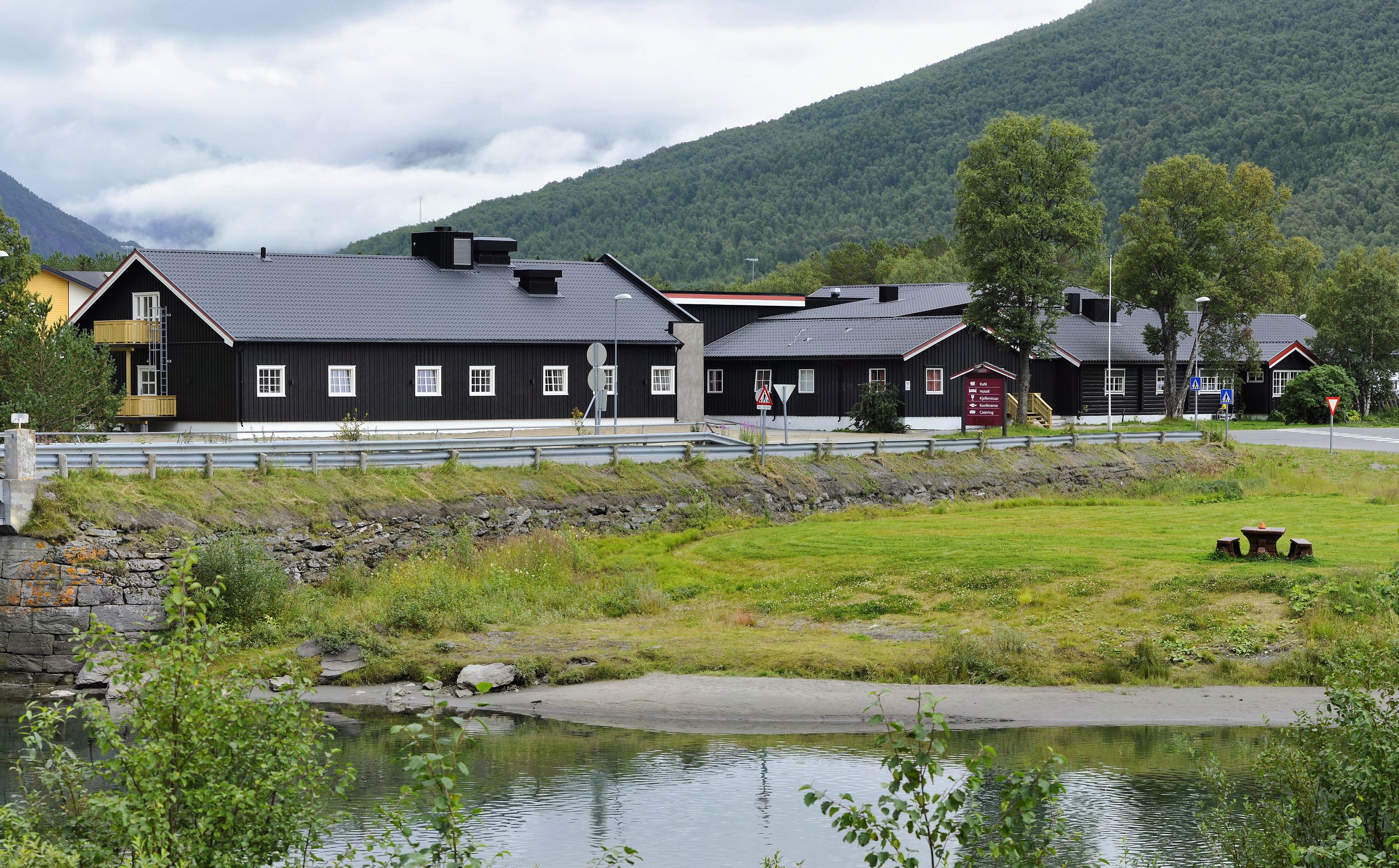 A row of black buildings with multiple windows and a small outdoor seating area.