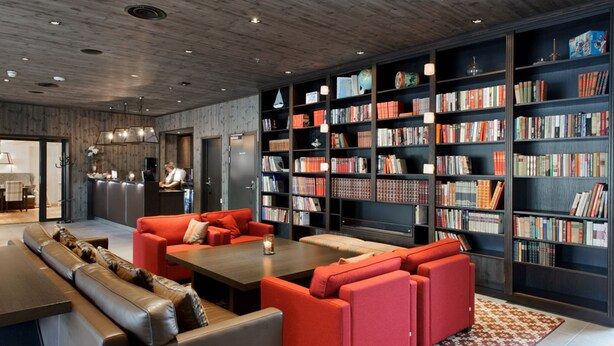 Une bibliothèque moderne avec des sièges en cuir, un plafond en bois et des étagères remplies de livres.