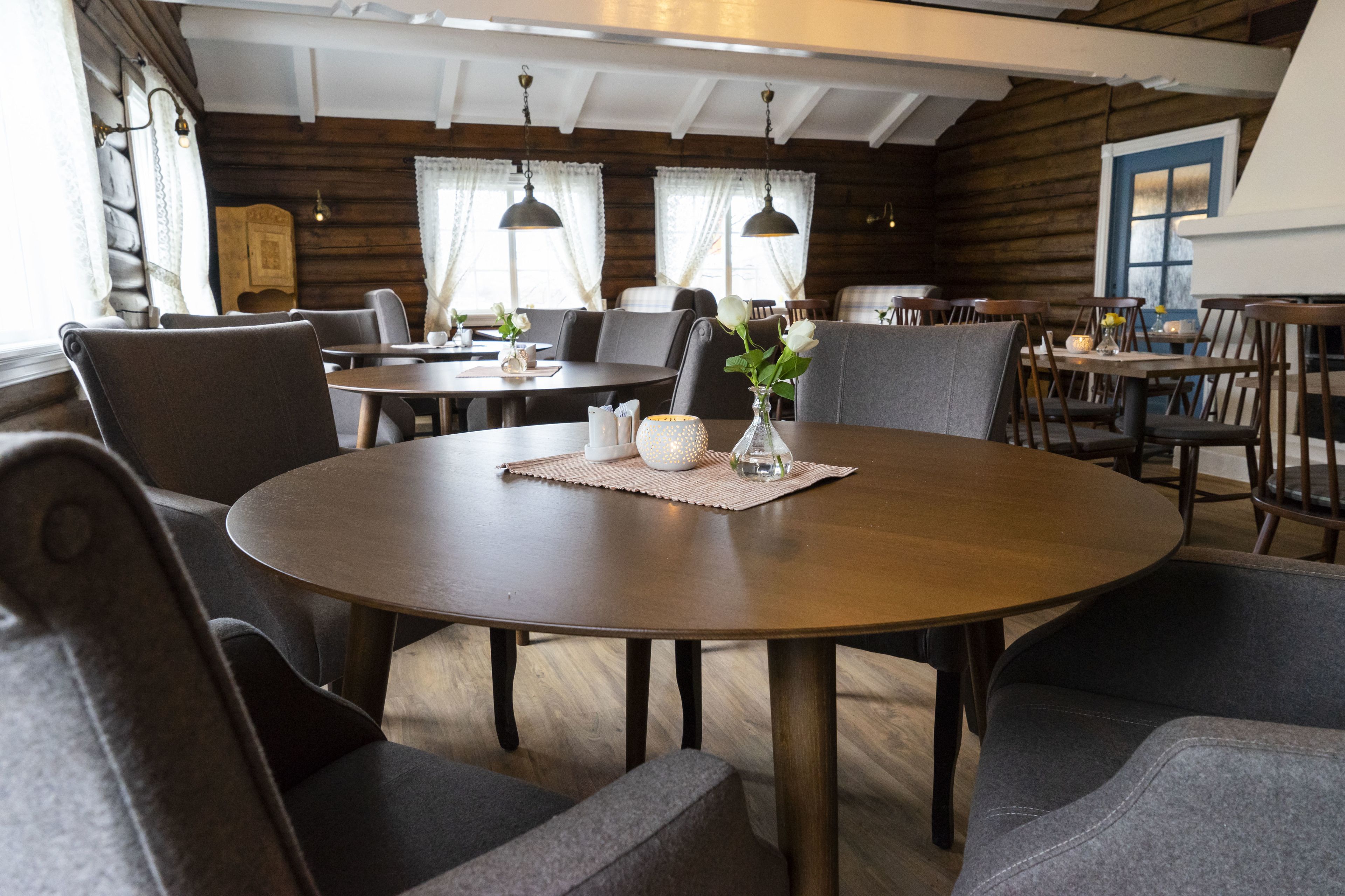 A cozy dining area with round tables, cushioned chairs, and pendant lighting.