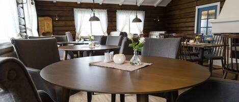 A cozy dining area with round tables, cushioned chairs, and pendant lighting.