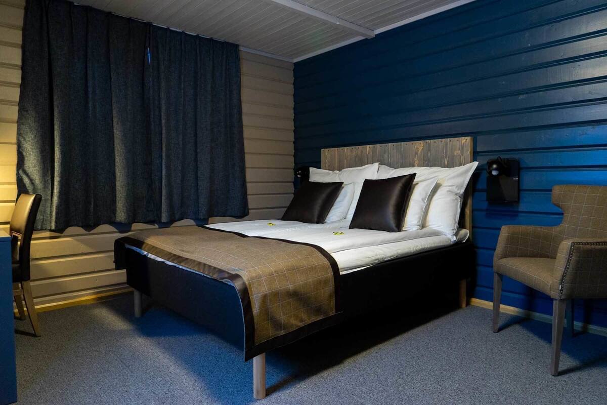 Ein Schlafzimmer mit einem Bett, einem Sessel, einem Schreibtisch und einer Lampe.