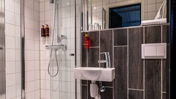 A modern bathroom with a glass-enclosed shower, a white sink, and a toilet.