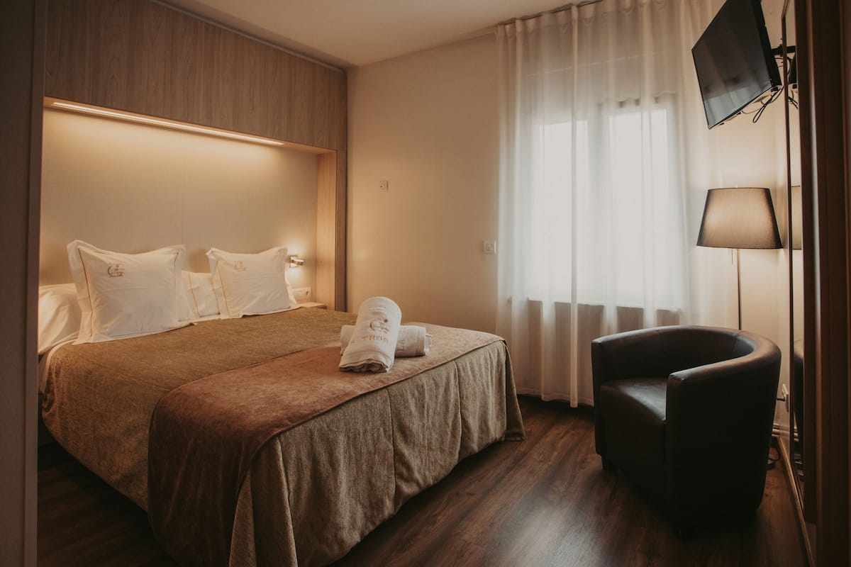A hotel room with a bed, a chair, and a TV.