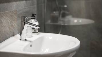 A bathroom with a white sink, a chrome faucet, and a glass-enclosed shower area.