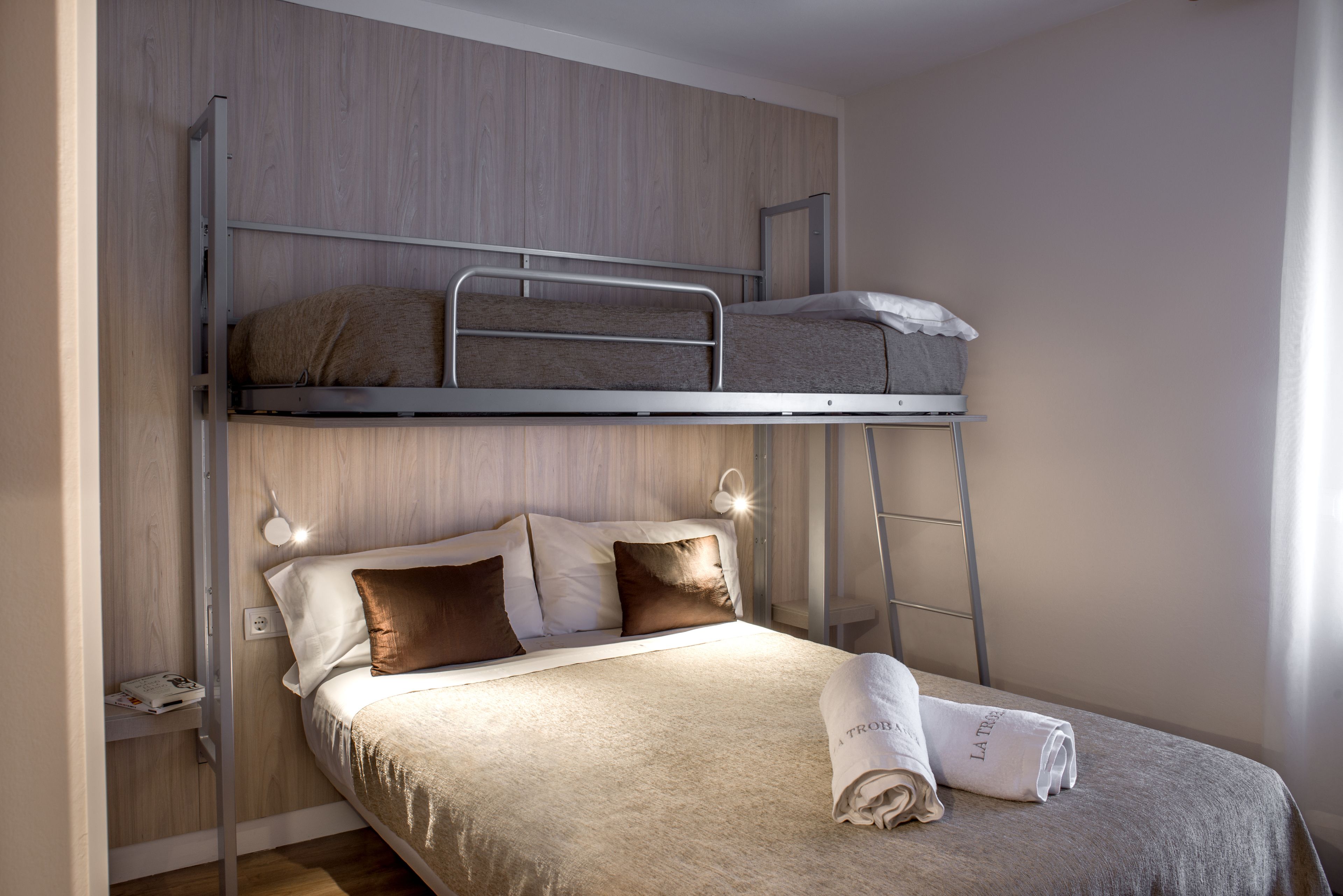 A bunk bed with a lower bed and a higher bunk. There is a folded towel on the lower bed.