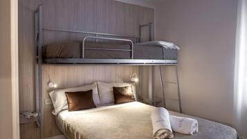 A bunk bed with a lower bed and a higher bunk. There is a folded towel on the lower bed.