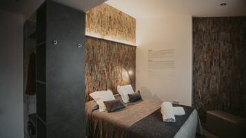 Quarto moderno com cama, almofadas, um banco e um painel fixado na parede.