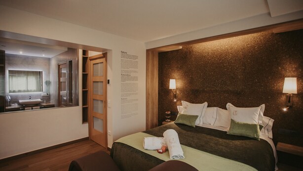 A hotel room with a large bed, a bedside table, a mirror, and a wall-mounted information board. - La Trobada Hotel Boutique (Ripoll)