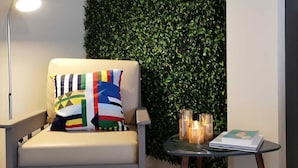 Ein modernes Zimmer mit einer Couch, einer Lampe, einem kleinen Tisch mit Kerzen und einer grünen Wand.