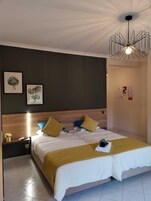 Una habitación de hotel moderna con una cama grande, cabecero de madera y una lámpara de techo original.