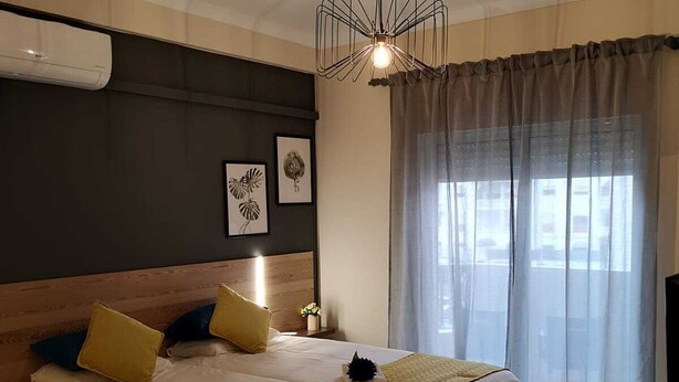 Ein modernes Hotelzimmer mit einem großen Bett, einer Deckenleuchte und einem mit Vorhängen versehenen Fenster.