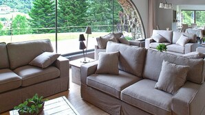 A spacious living area with multiple sofas and a large window offering a view of greenery. - L'Hotelet del Bac (Camprodon)