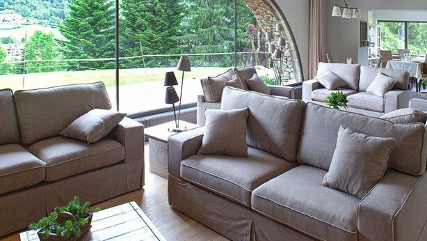 A spacious living area with multiple sofas and a large window offering a view of greenery. - L'Hotelet del Bac (Camprodon)