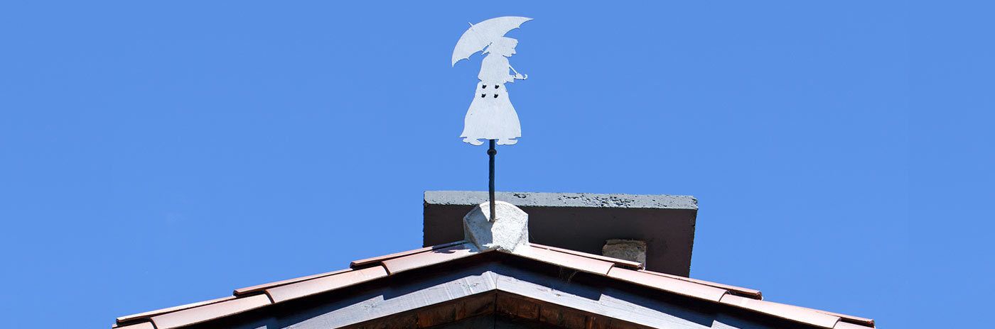 A building with a peaked roof and a white statue of a figure with outstretched arms on top.