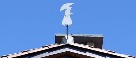 A building with a peaked roof and a white statue of a figure with outstretched arms on top.