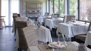 A dining area with wicker chairs and tables, a buffet area with glassware, and a view of greenery outside. - L'Hotelet del Bac (Camprodon)