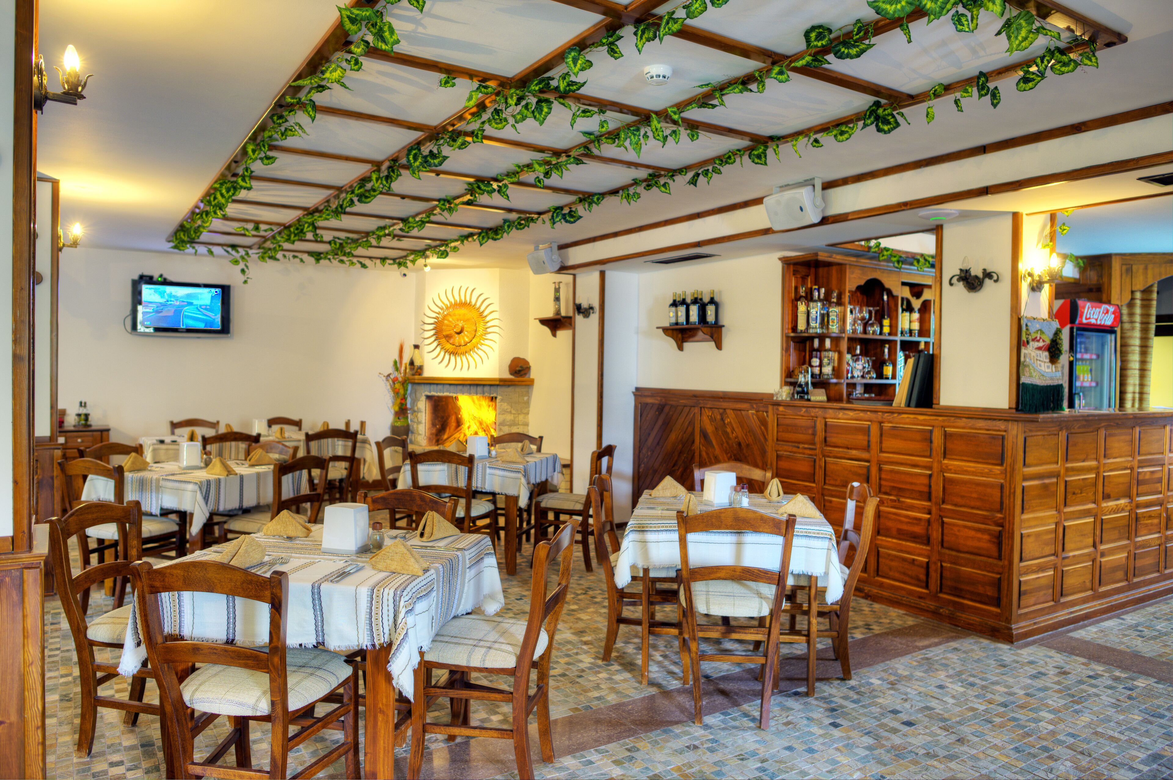 A restaurant with wooden tables and chairs, a bar area, and a fireplace.
