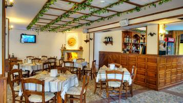 A restaurant with wooden tables and chairs, a bar area, and a fireplace.