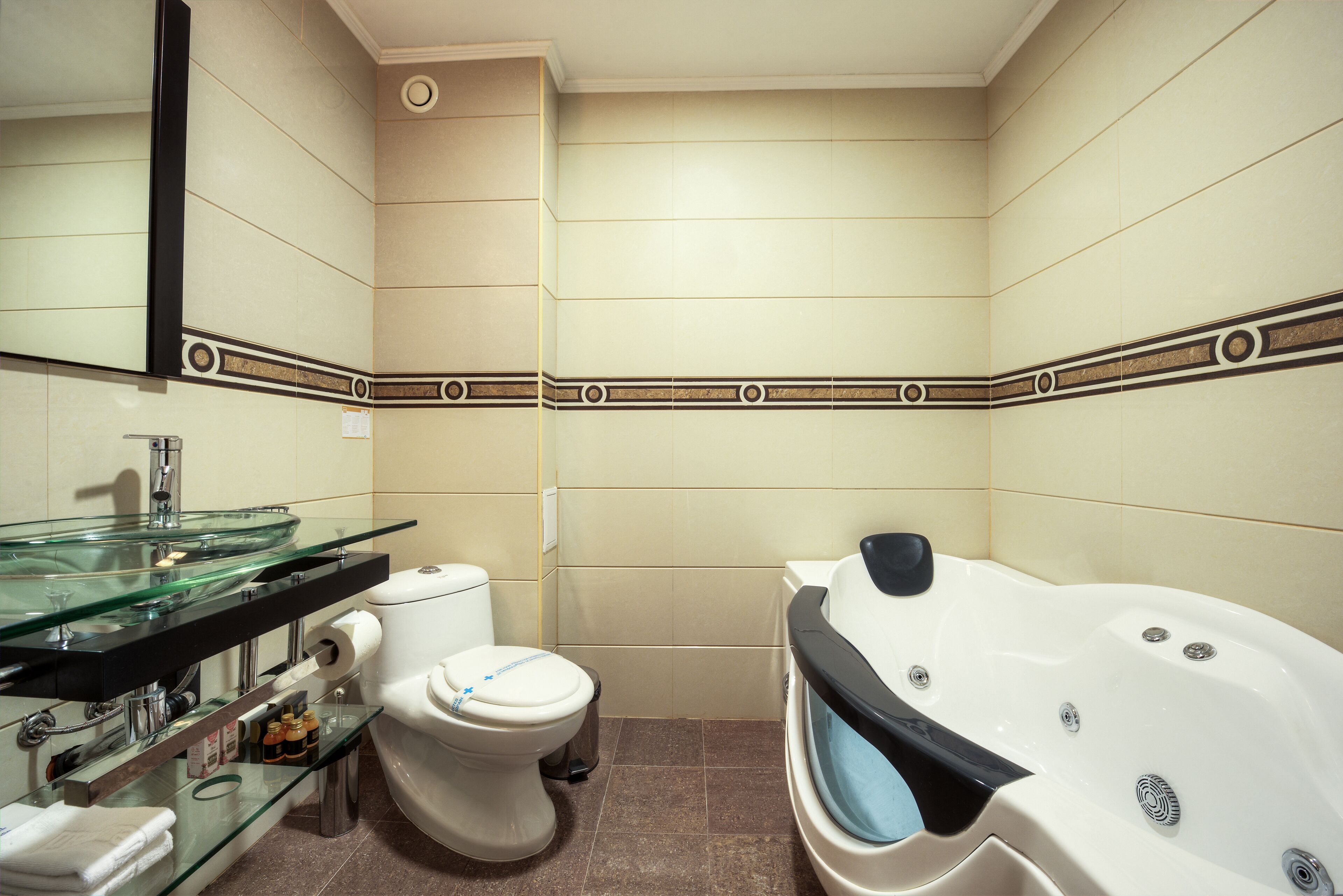 A bathroom with a glass sink, a toilet, and a bathtub.