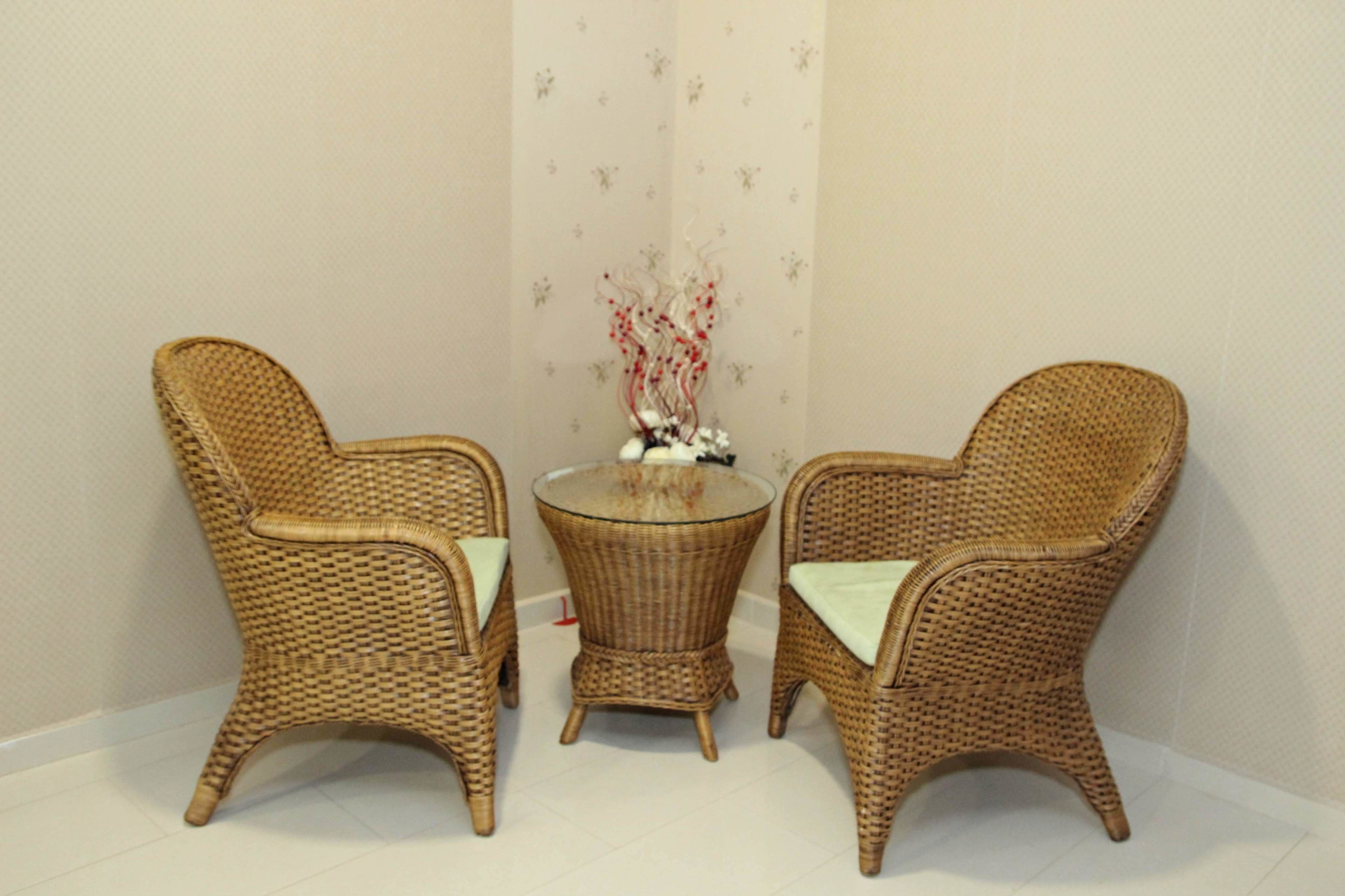 A corner with two wicker chairs and a small round table with a decorative item on it.