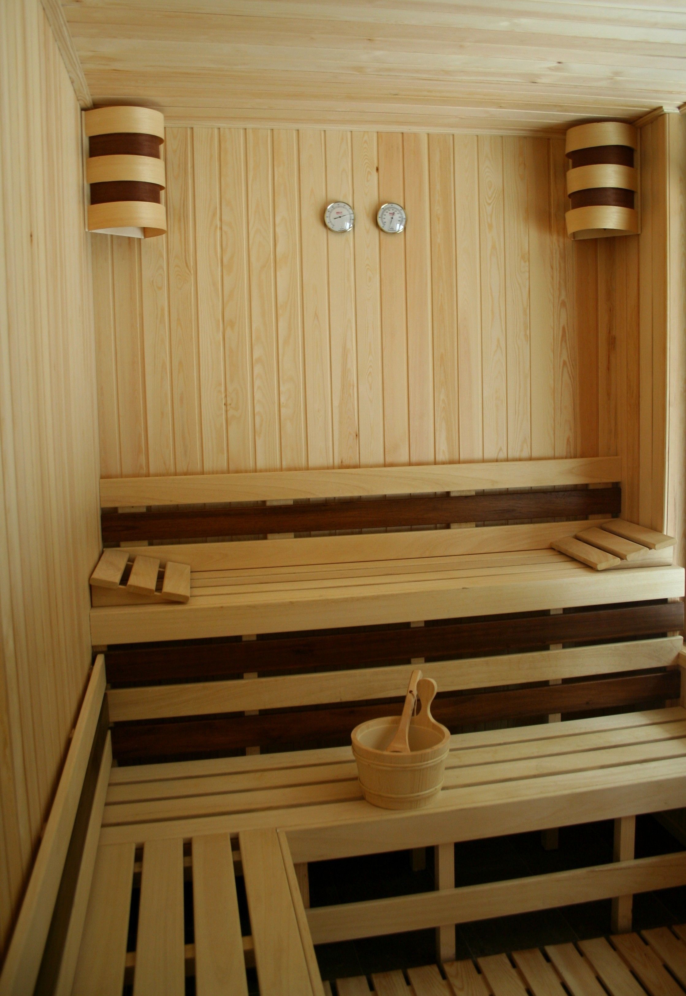 A wooden sauna with benches and a wooden bucket.