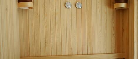 A wooden sauna with benches and a wooden bucket.
