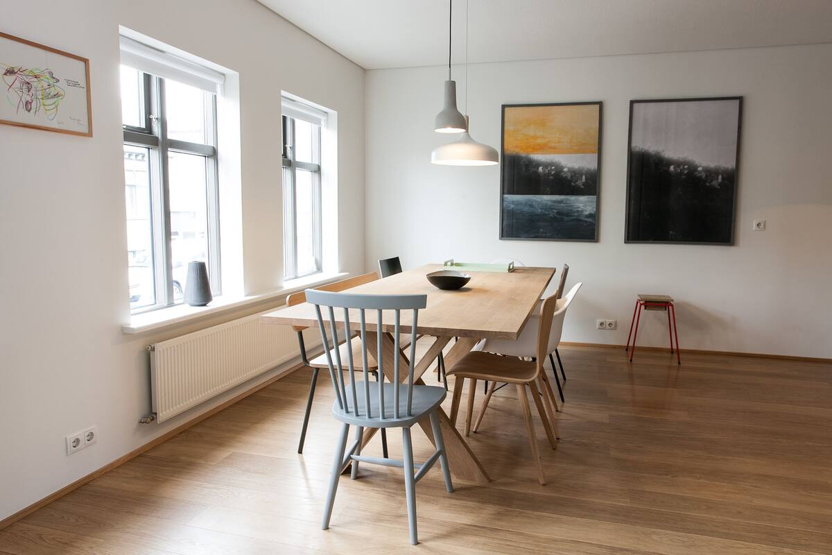A dining area with a wooden table, chairs, and pendant lighting.