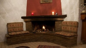 A cozy room with a fireplace, two patterned armchairs, and two rugs. - Petrospito Pool Apt ''Katoi'', Faros Avlida (Chalcis)
