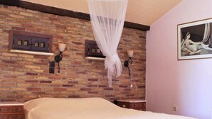 Un dormitorio con pared de ladrillo, una cama con dosel, una mesita de noche y una lámpara de pared.