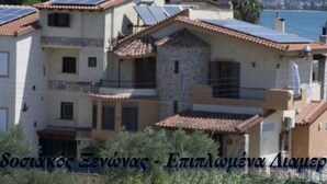 Un edificio de varios pisos con paneles solares en el techo, balcones y fachada de piedra.