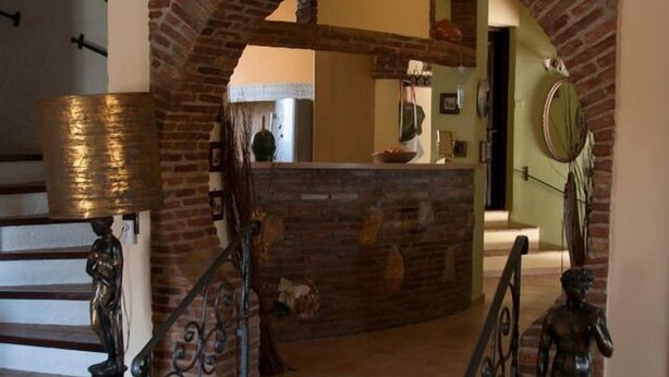 Una escalera con un arco de ladrillo que lleva a una zona de cocina.