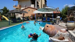 Una piscina con gente, un tobogán y una gran escultura en forma de barril.