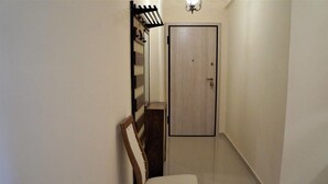 A narrow hallway with a wooden chair, a coat rack, and a door. - Shiny Modern Apartment • 1' to Metro Station (Athens)